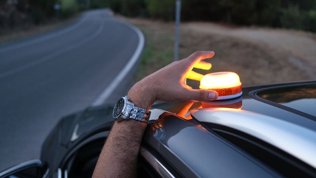 Balise allumée posée sur le toit d'une voiture au bord d'une route au crépuscule