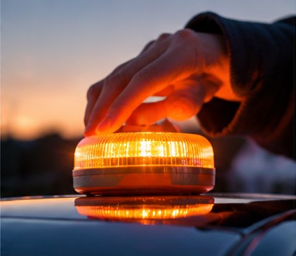 Une main pose la balise allumée sur le toit d'une voiture